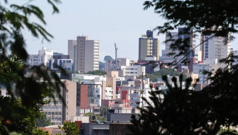 Imagem mostra prédios de Curitiba com uma moldura feita com árvores.