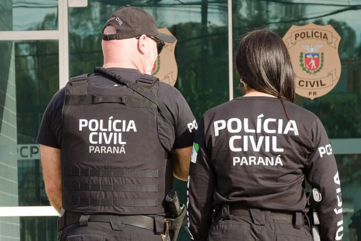 Imagem mostra dois policiais civis de costas com a logo da corporação.