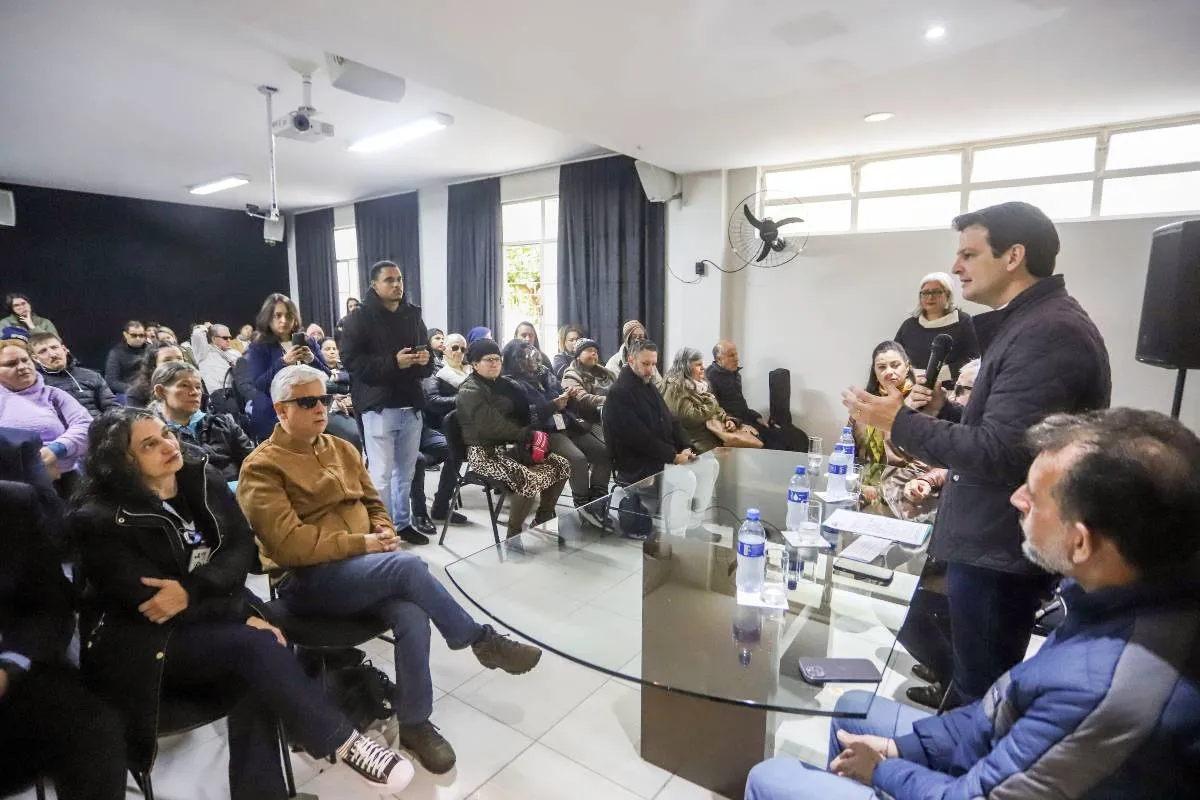 Imagem mostra pessoas em uma apresentação dentro de um auditório.