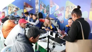 Imagem mostra um balcão de atendimento om computadores e pessoas