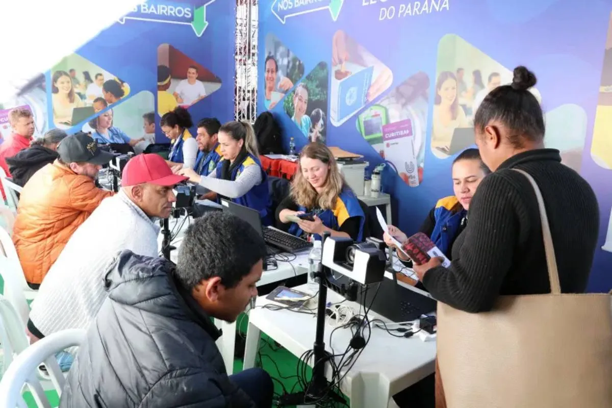 Imagem mostra um balcão de atendimento om computadores e pessoas