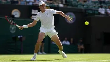 João fonseca em ação, se posiciona para acertar uma raquetada na bolinha, no gramado de Wimbledon