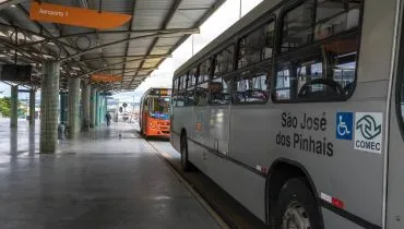Imagem mostra um ônibus prata estacionado em um terminal.
