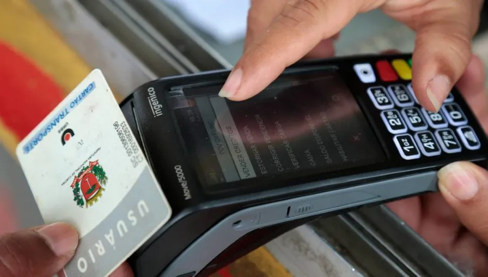 Imagem mostra uma pessoa recarregando um cartão transporte numa maquininha