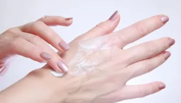 Imagem mostra mulher passando creme nas mãos