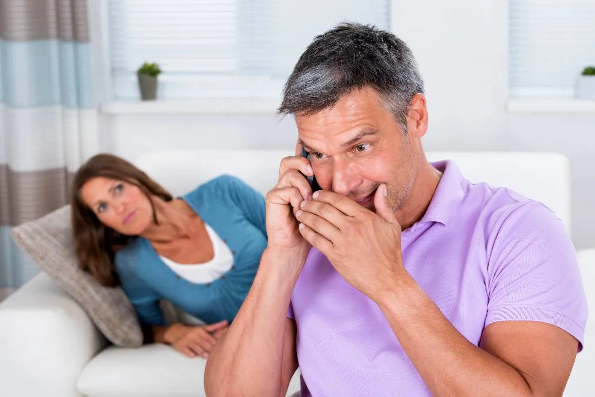 Imagem mostra um homem falando escondido no celular