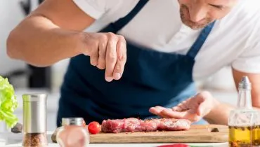 Imagem mostra homem temperando carne e utilizando temperos naturais