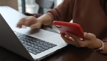 Imagem mostra mulher mexendo em computador e celular