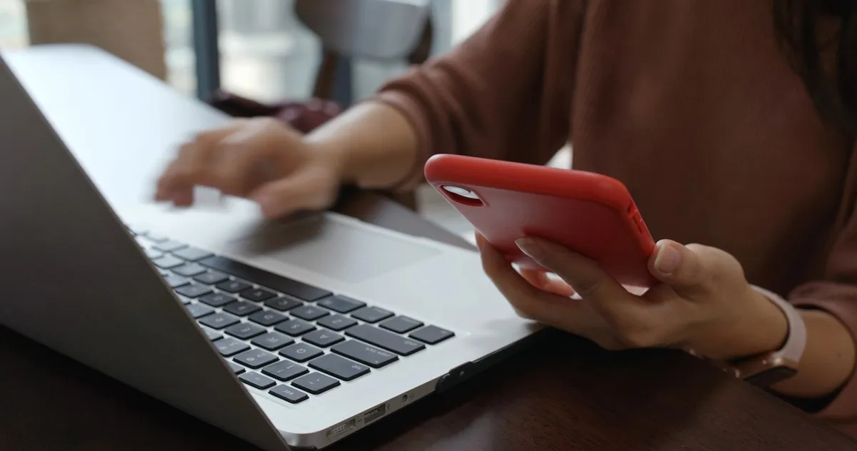 Imagem mostra mulher mexendo em computador e celular