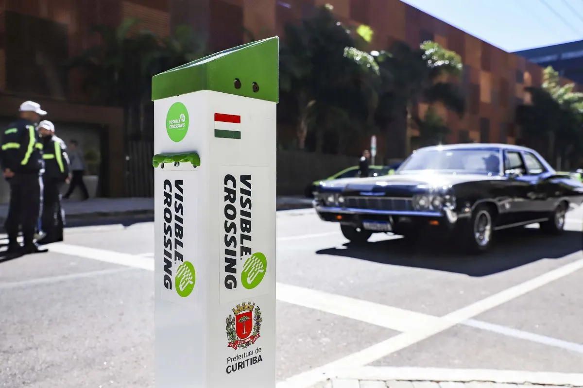 Imagem mostra agente de trânsito atravessando a rua, com novo eqipamento em forma de totem no primeiro plano