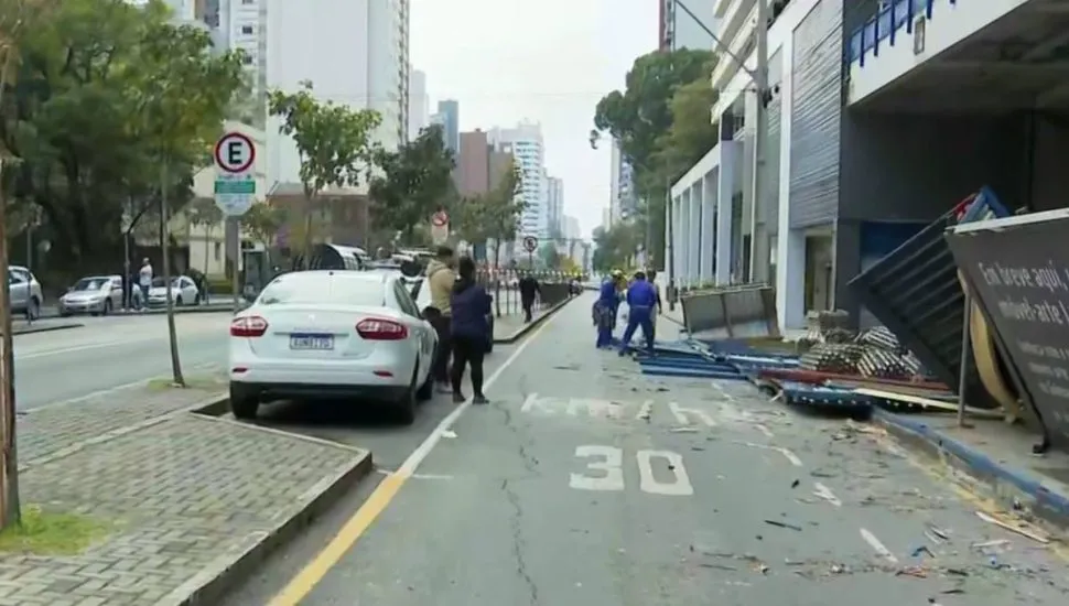 Imagem mostra uma rua de Curitiba com trabalhadores limpando uma calçada.