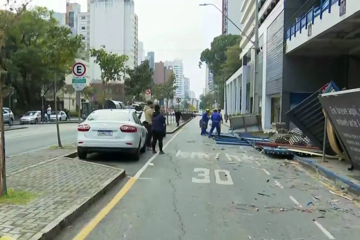 Imagem mostra uma rua de Curitiba com trabalhadores limpando uma calçada.