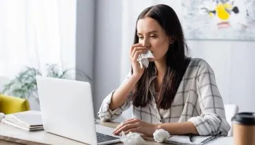 Imagem mostra mulher com alergia, limpando o nariz