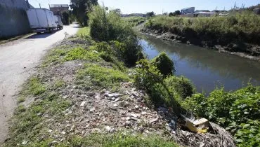 Imagem mostra muito lixo na beira de um rio de Curitiba