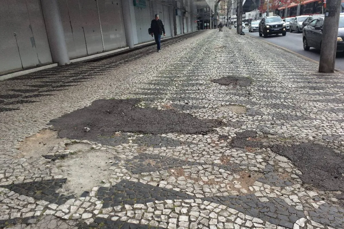 Imagem mostra uma calçada destruída em Curitiba.