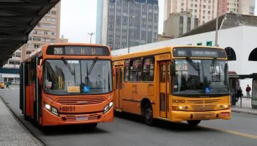 Imagem mostra dois ônibus estacionados em uma praça de Curitiba