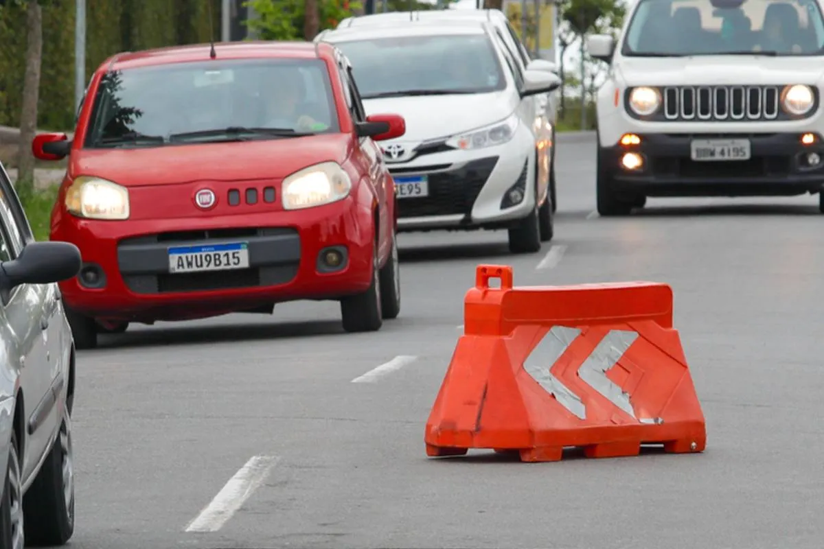 Imagem mostra carros desviando de um sinalizador de via em Curitiba.