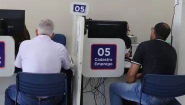 Imagem mostra pessoas em um guichê de atendimento ao público.