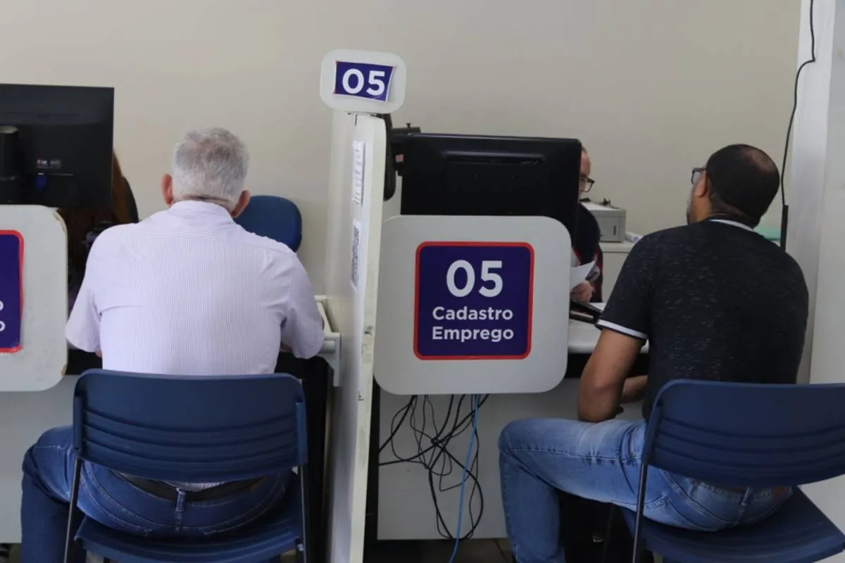 Imagem mostra pessoas em um guichê de atendimento ao público.