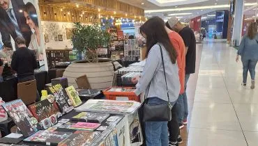 Pessoas procuram por vinis em uma mesa comprida colocada no corredor do Shopping