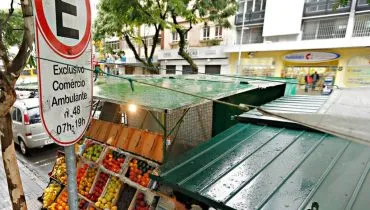 Imagem mostra uma placa de comercio ambulante em Curitiba, com uma barraca de frutas