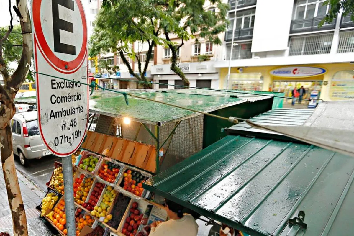 Imagem mostra uma placa de comercio ambulante em Curitiba, com uma barraca de frutas