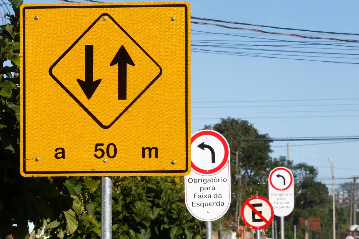 Imagem mostra uma sinalização de trânsito com placas amarelas e brancas