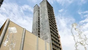 Imagem mostra um prédio de Curitiba com céu azul com nuvens.