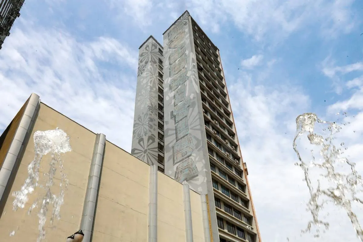 Imagem mostra um prédio de Curitiba com céu azul com nuvens.