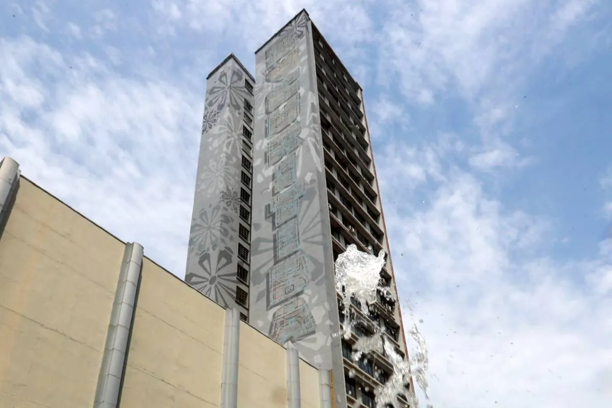 Imagem mostra um prédio de Curitiba com céu azul com nuvens.