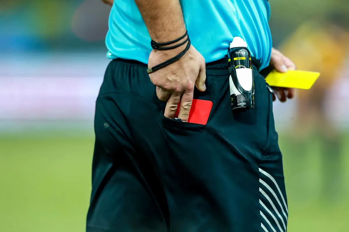 Imagem mostra árbitro de futebol e cartões amarelo e vermelho