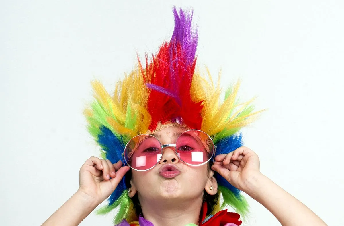 criança usa óculos colorido e cabelo penteado de forma engraçada, cheio de cores