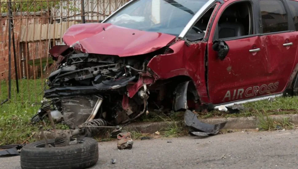 Imagem mostra um carro vermelho acidentado.