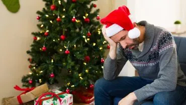 Imagem mostra árvore de Natal e homem triste