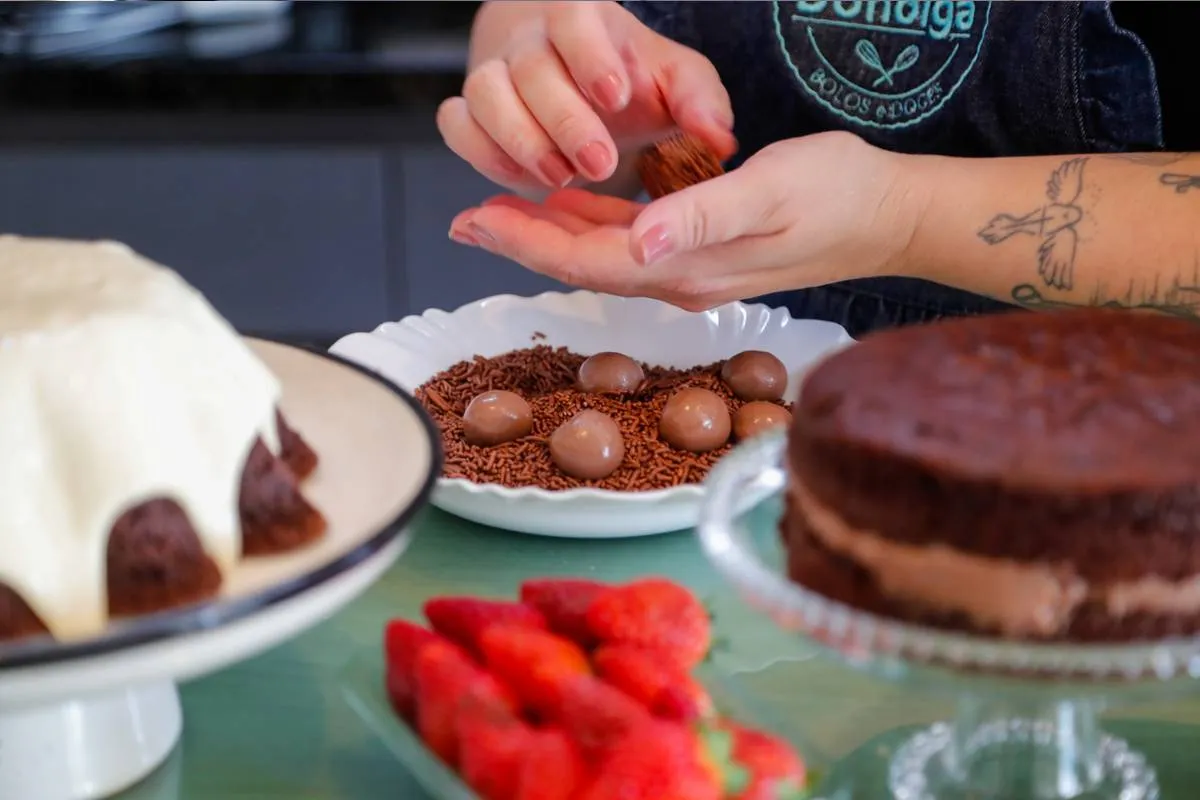 Imagem mostra uma confeiteira fazendo um belo e saboroso bolo.