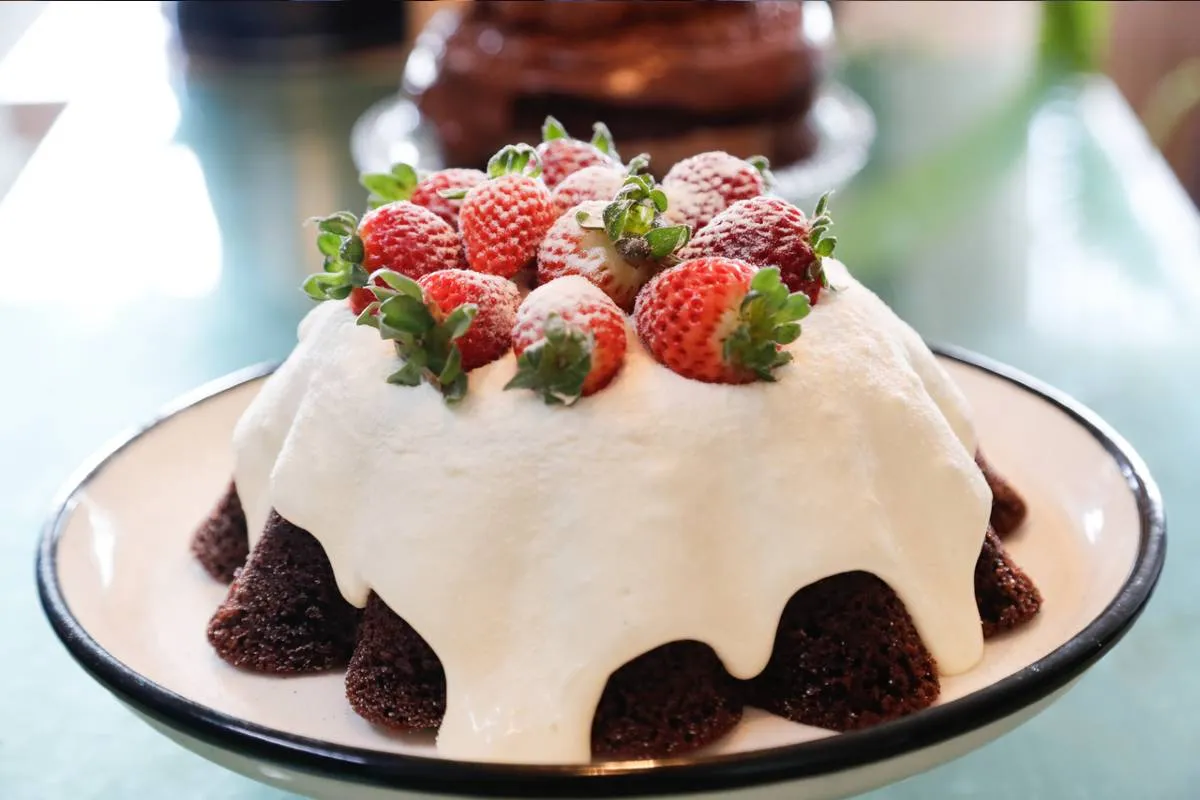 Imagem mostra uma confeiteira fazendo um belo e saboroso bolo.