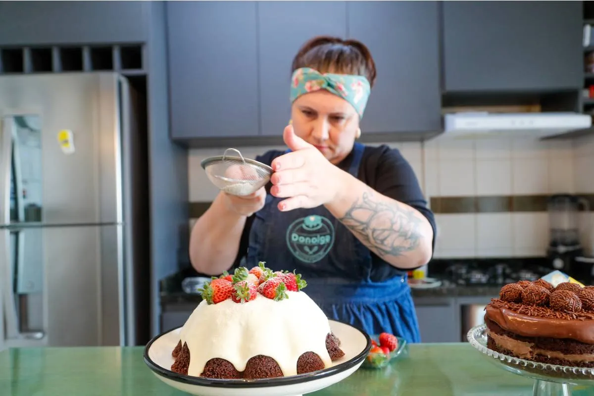Imagem mostra uma confeiteira fazendo um belo e saboroso bolo.