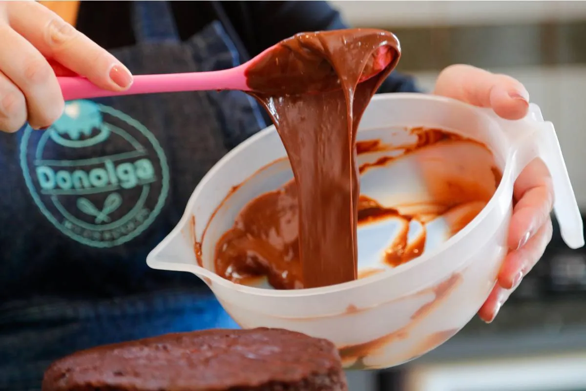 Imagem mostra uma confeiteira fazendo um belo e saboroso bolo.