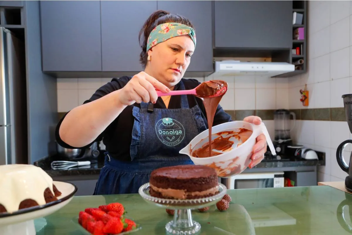 Imagem mostra uma confeiteira fazendo um belo e saboroso bolo.