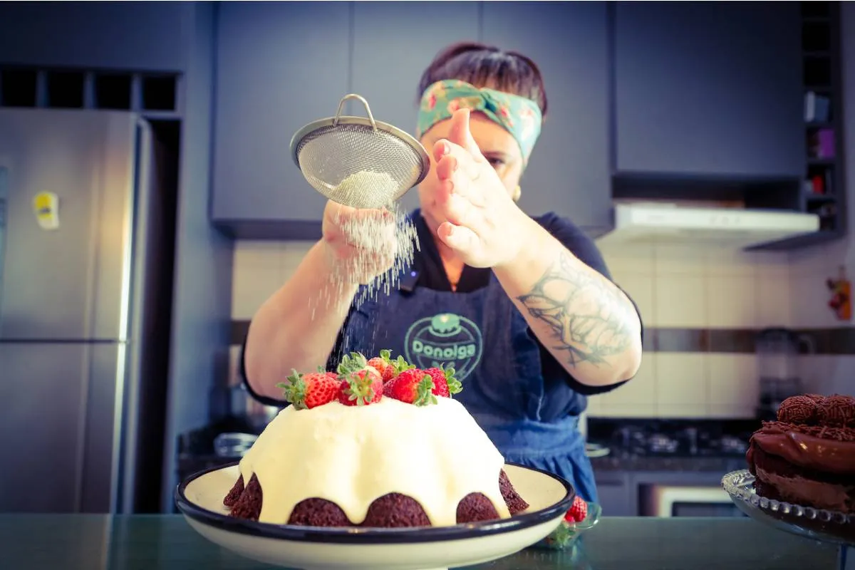 Imagem mostra uma confeiteira fazendo um belo e saboroso bolo.