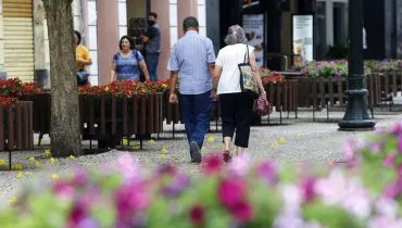 Imagem mostra duas pessoas andando na Rua XV, em Curitiba.
