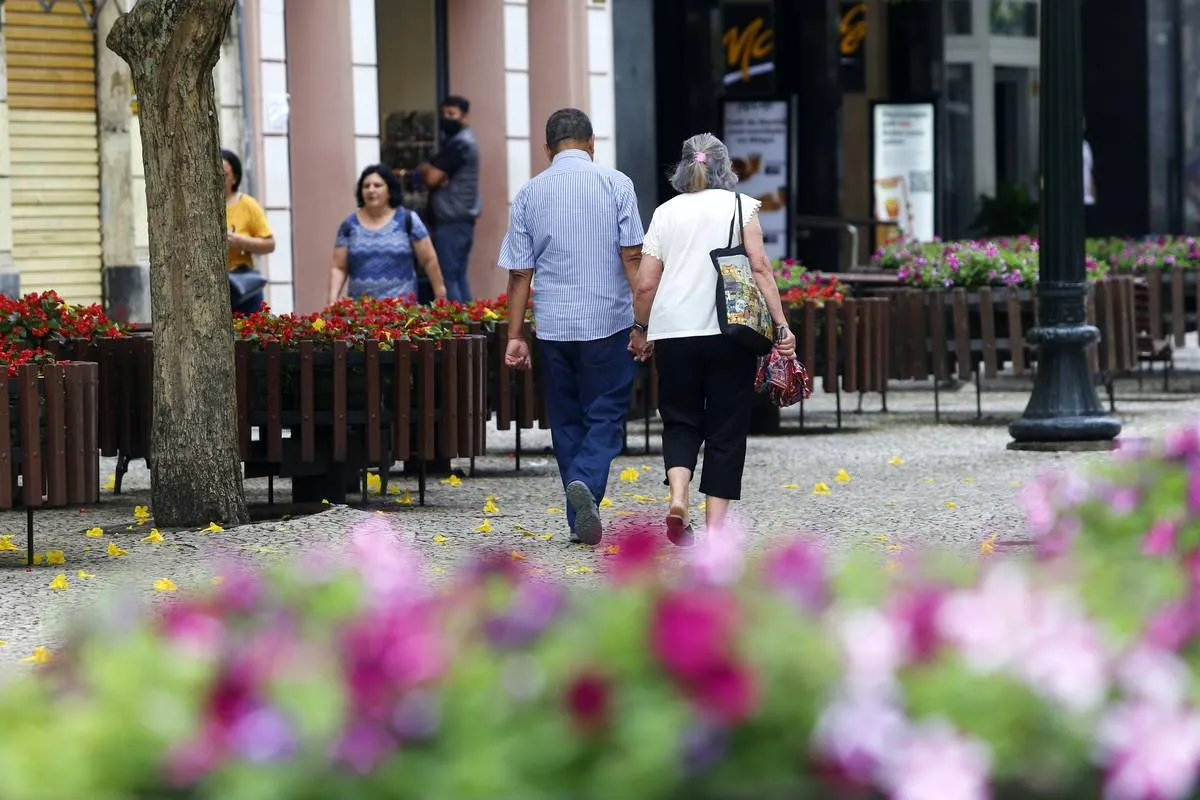 Imagem mostra duas pessoas andando na Rua XV, em Curitiba.