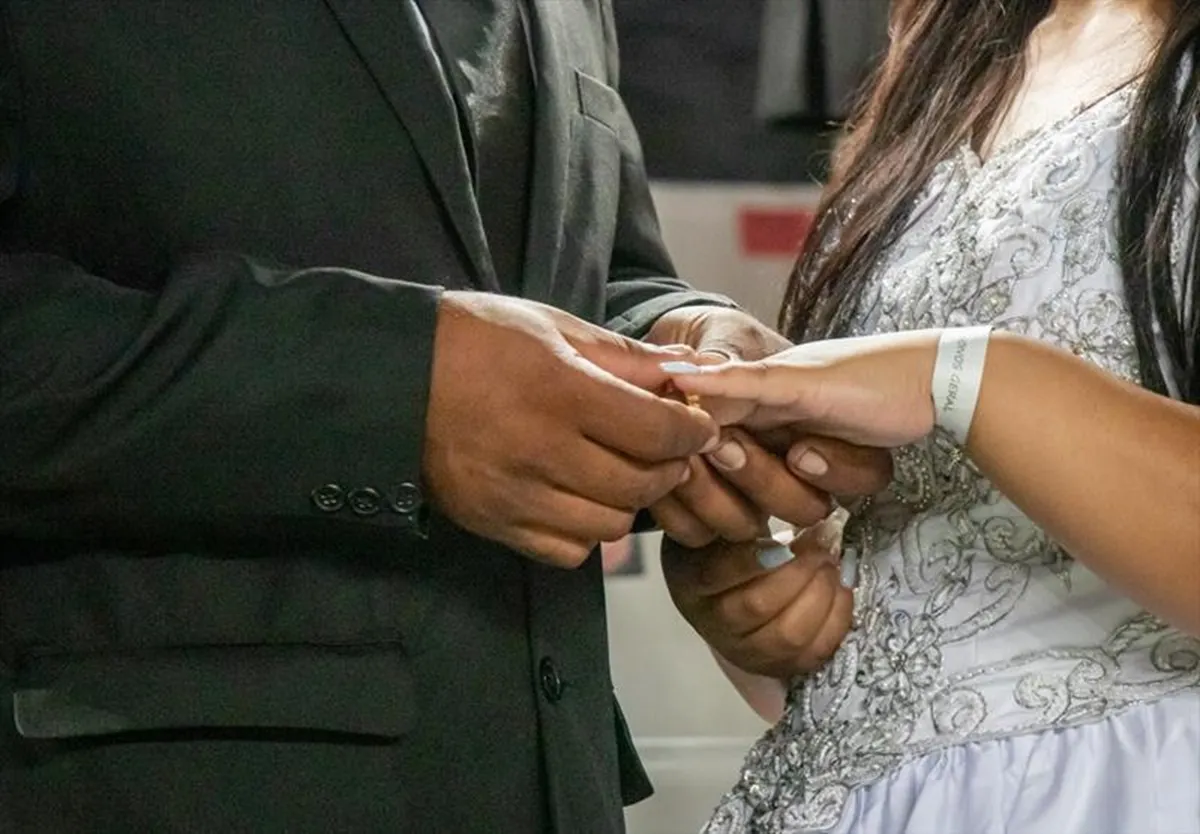 Imagem mostra casal trocando alianças em casamento