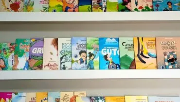 Imagem mostra uma prateleira com vários livros enfileirados