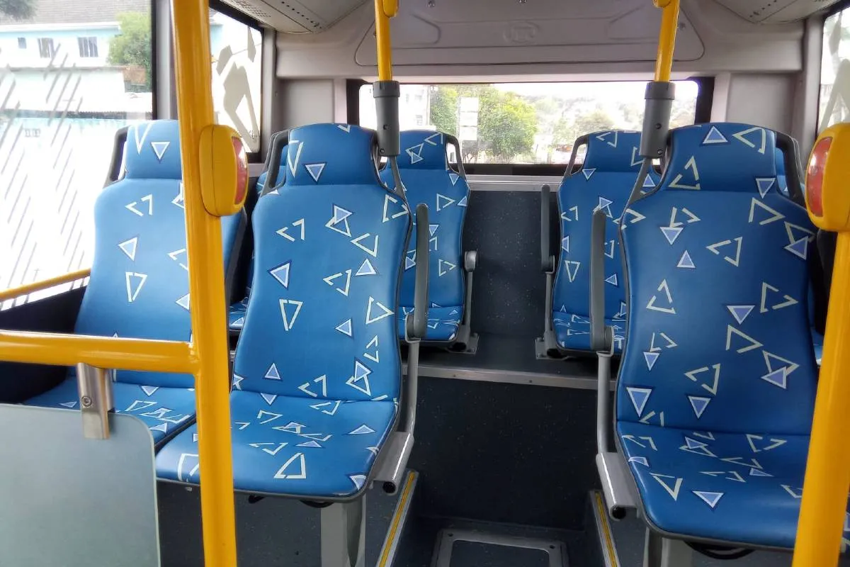 Imagem mostra um micro ônibus elétrico  de cor verde flagrado circulando pelas ruas de Curitiba em uma linha de transporte coletivo.