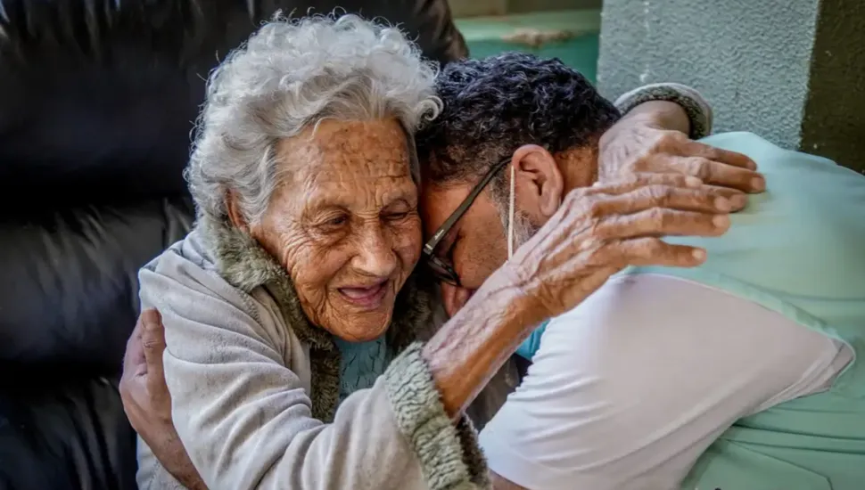 Imagem mostra homem abraçando mulher idosa