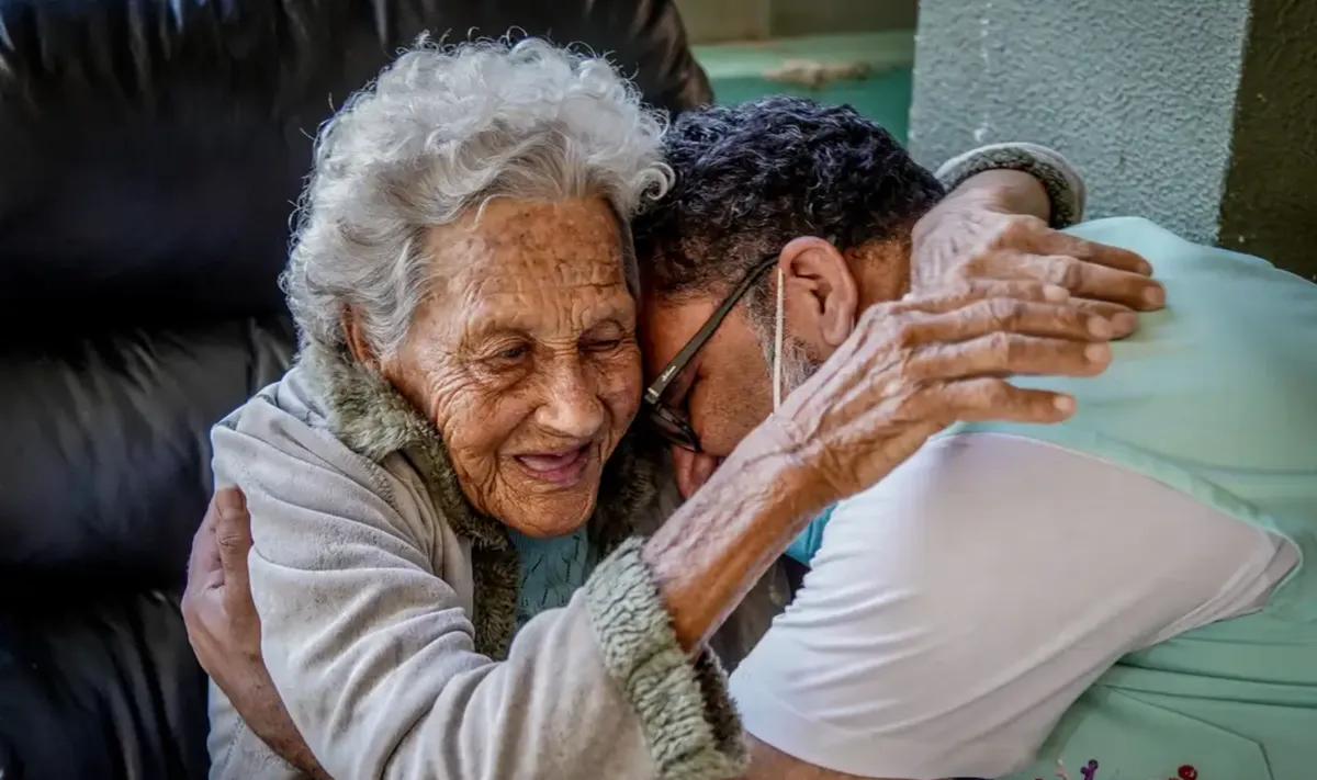 Imagem mostra homem abraçando mulher idosa