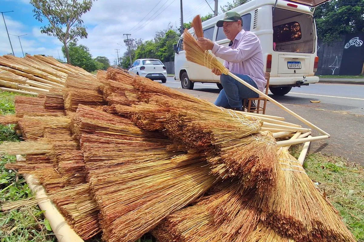 Imagem mostra um homem montando as tradicionais vassouras de palha em Curitiba. 