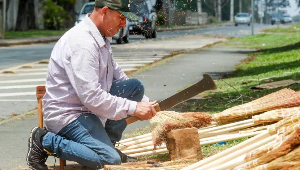 Imagem mostra um homem montando as tradicionais vassouras de palha em Curitiba.