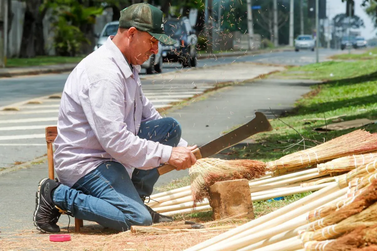 Imagem mostra um homem montando as tradicionais vassouras de palha em Curitiba. 